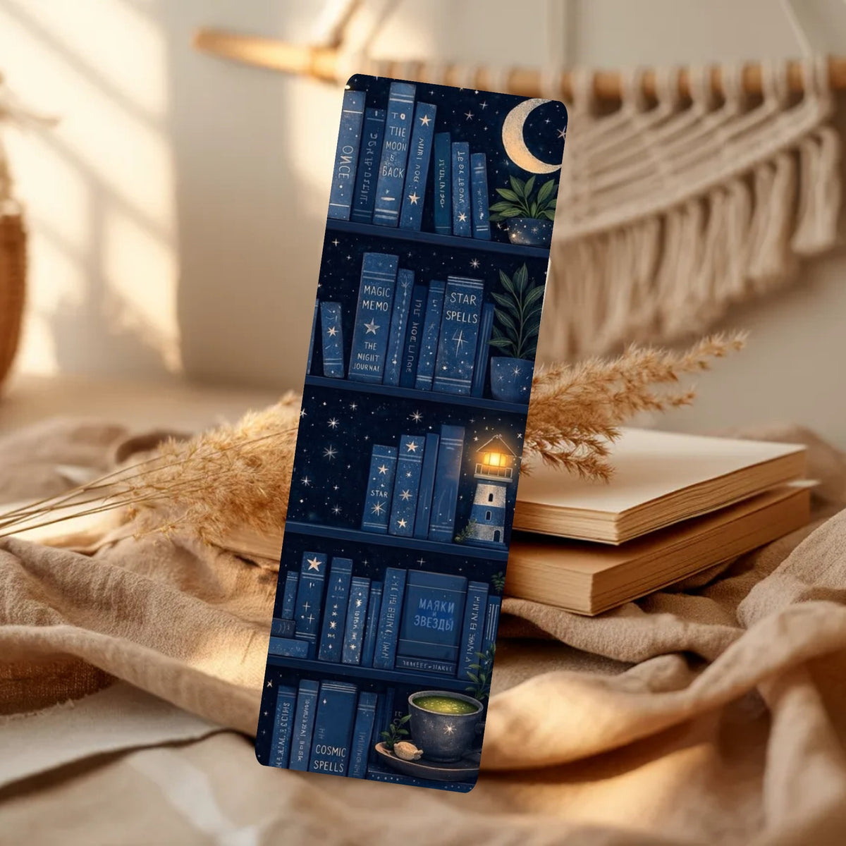 A slim phone case with a dark blue bookshelf pattern featuring stars, a crescent moon, and cozy book-themed illustrations, displayed in a warm, styled room setting with books and dried grass.
