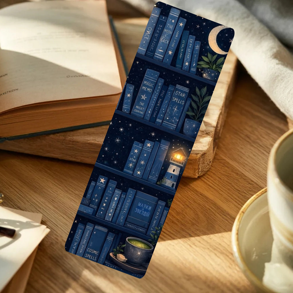 A slim rectangular bookmark with a navy blue bookshelf illustration, leaning on a wooden tabletop beside an open book and a cup.